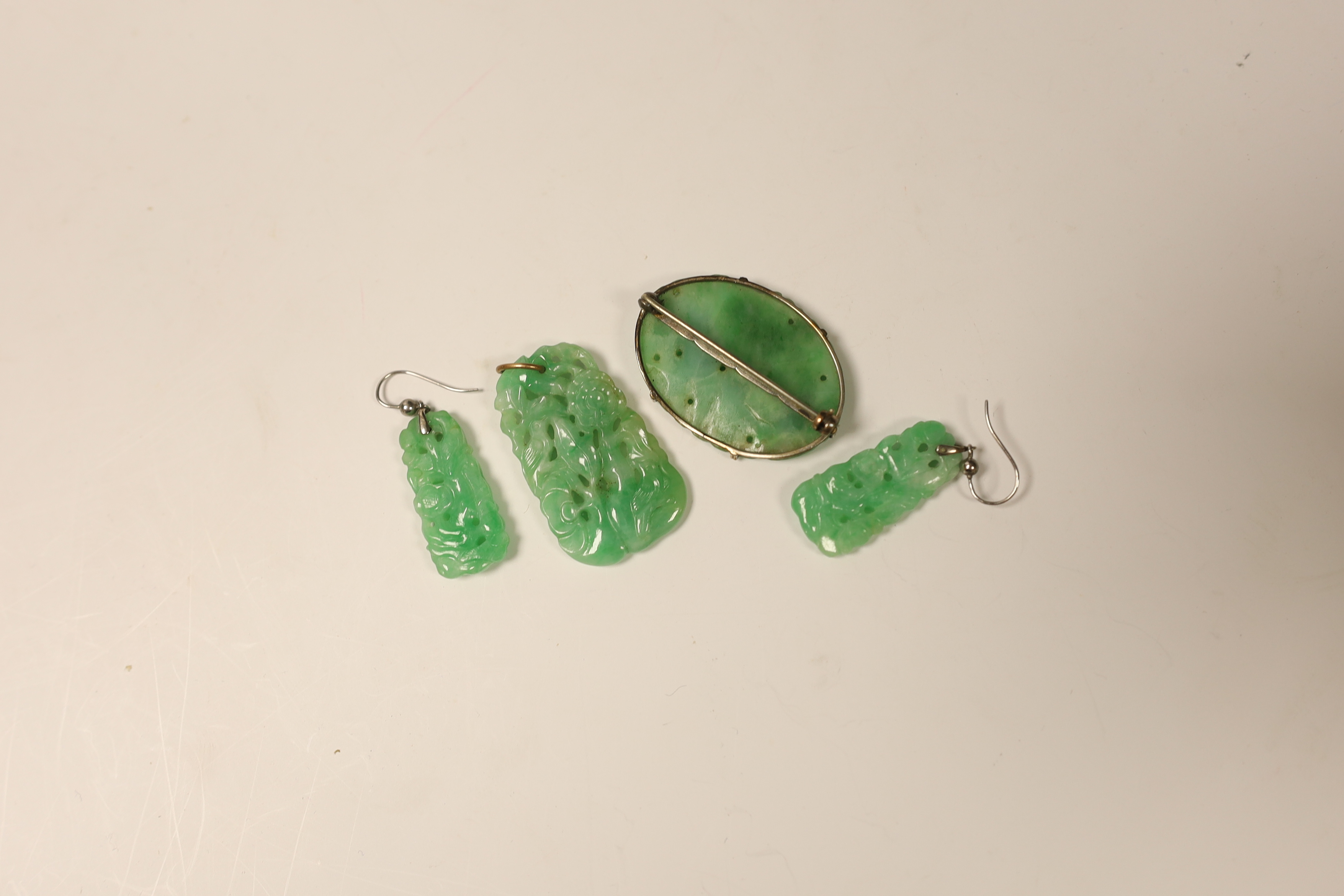 Four items of white metal mounted carved jade jewellery, comprising a brooch, 37mm, a pendant and pair of earrings.